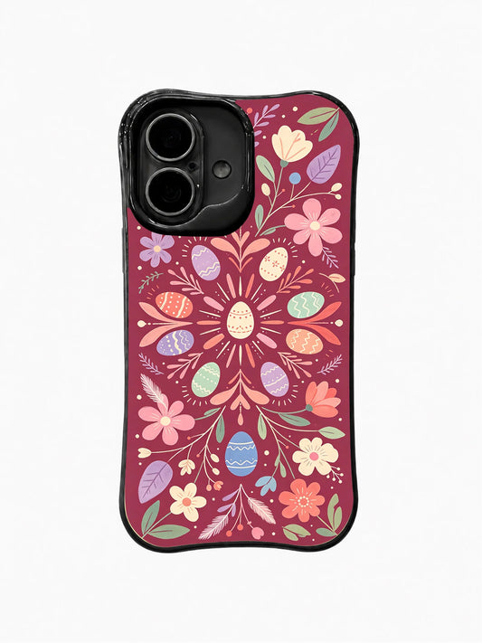 Black iPhone 16 Plus case with a symmetrical pink floral medallion, egg-shaped petals, leafy branches, and small multicolor blossoms
