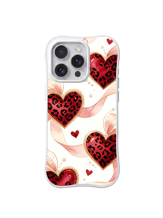 Clear iPhone 16 Pro case with red leopard-print hearts, small red hearts, pale pink curling ribbons, and pearl-like dots on cream