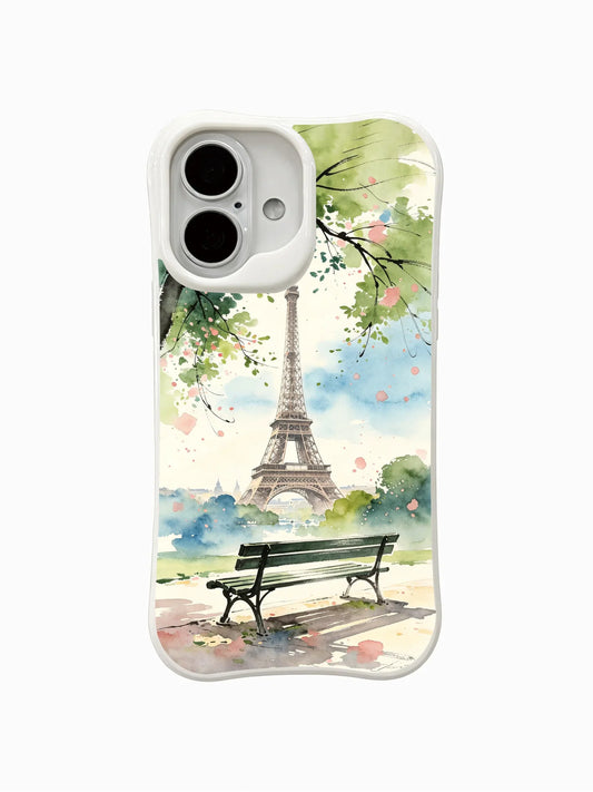 Cream iPhone 16 case with a watercolor view of the Eiffel Tower, a park bench, leafy branches, and soft pink flowers
