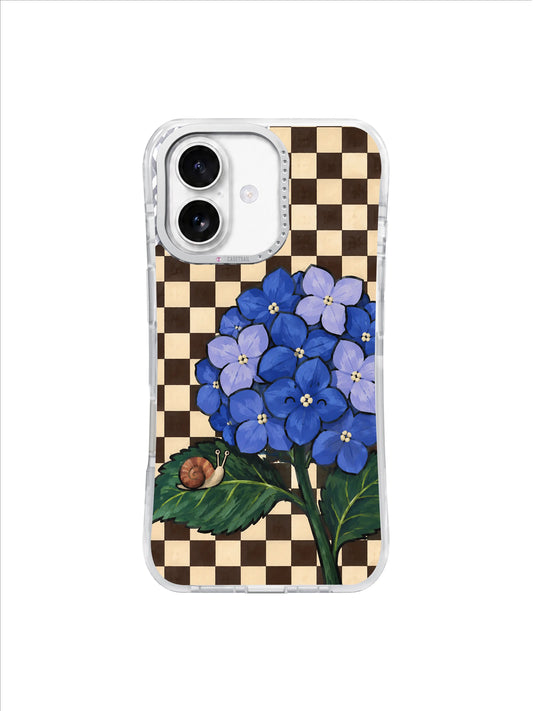 Blue Hydrangea Listener artwork on an iPhone 17 case with ultramarine florets, green leaves, a small terracotta snail and espresso-vanilla checks.