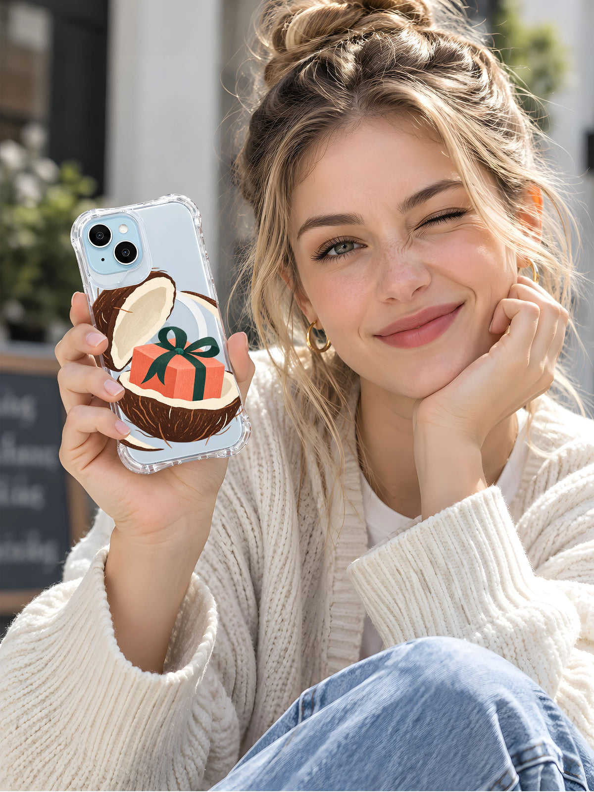 Woman displaying the Coconut Parcel Orbit transparent iPhone case