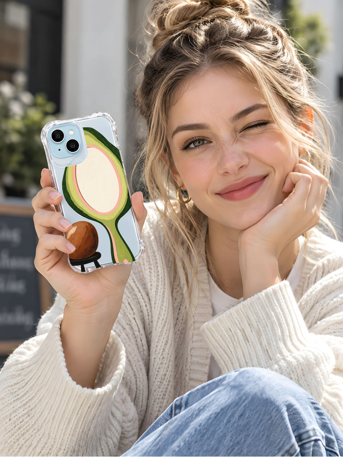 Woman displaying the Avocado Mirror Pause transparent iPhone case