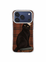 Black cat seated against warm brown tartan in an imperfect-crown story iPhone 17 Pro case pattern