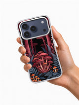 Hand holding a phone case printed with burgundy mushrooms, blue-gray ferns, orange fungi, and pale stars
