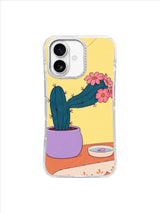 Cactus in a lilac pot extending a flower-covered branch beside a fallen-petal dish