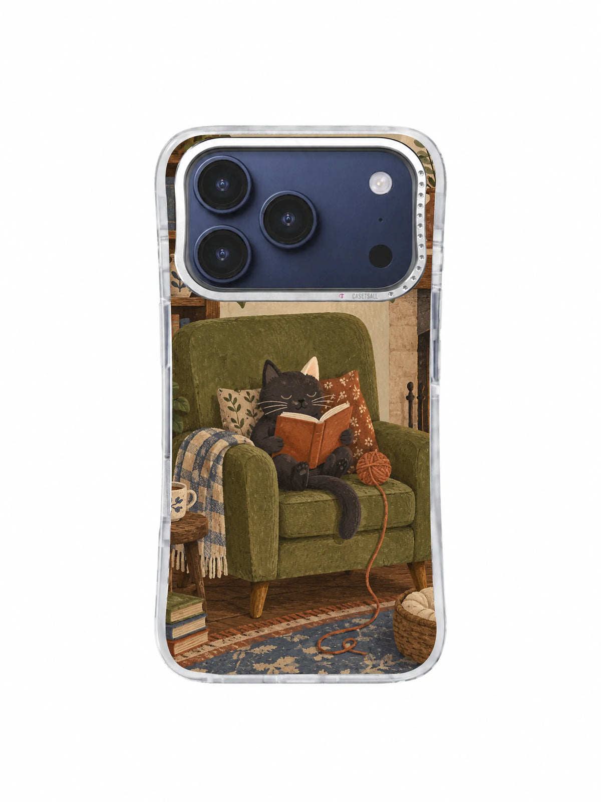 Charcoal cat nested in an olive armchair with a terracotta book and patterned rug on an iPhone 17 Pro case