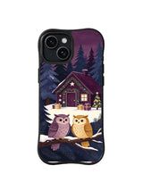 Black iPhone 14 case showing twin owls on a pine branch before a plum-roof Christmas reading cottage