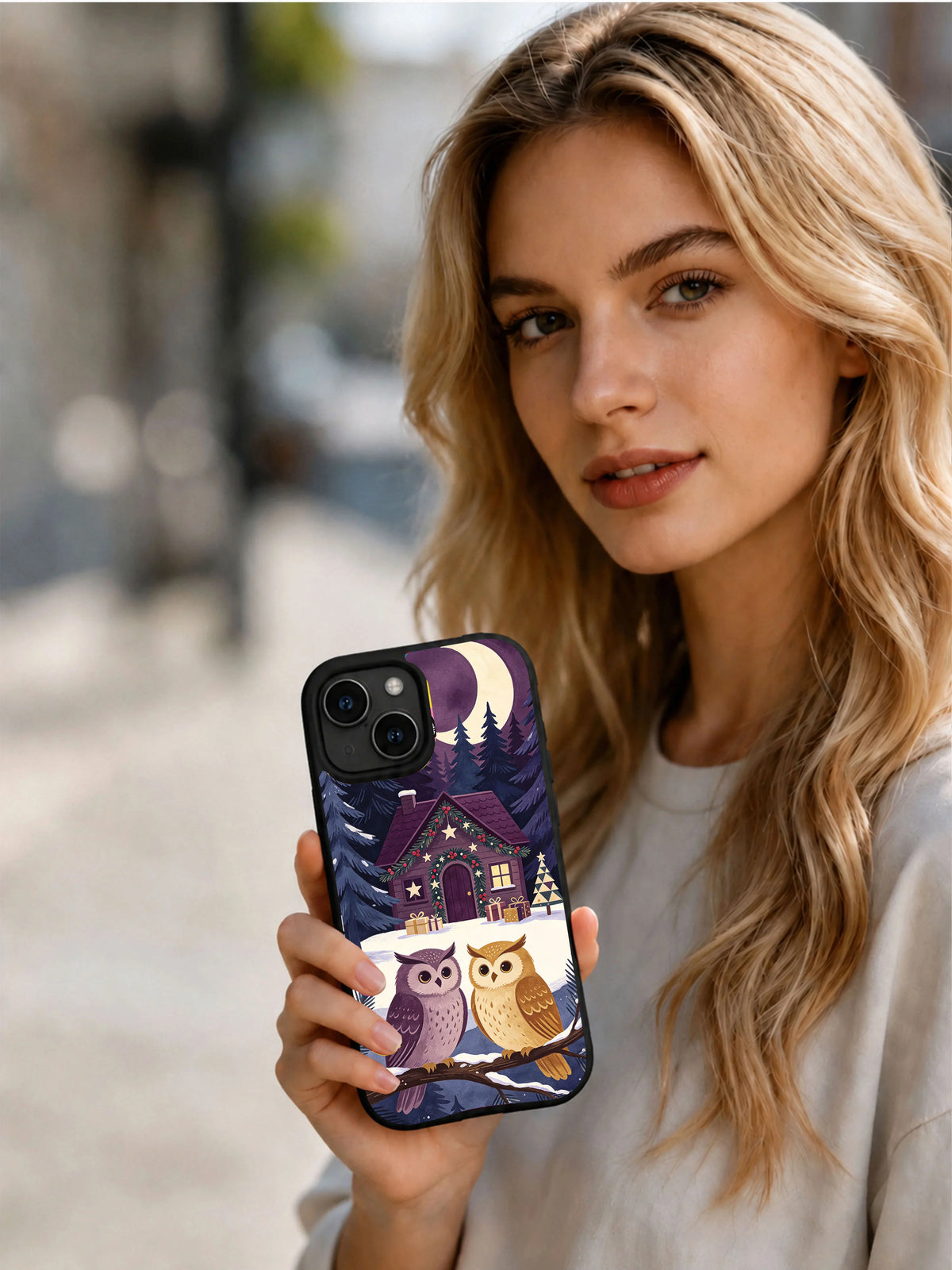 Person holding the black Christmas Owl Library iPhone 14 case outdoors