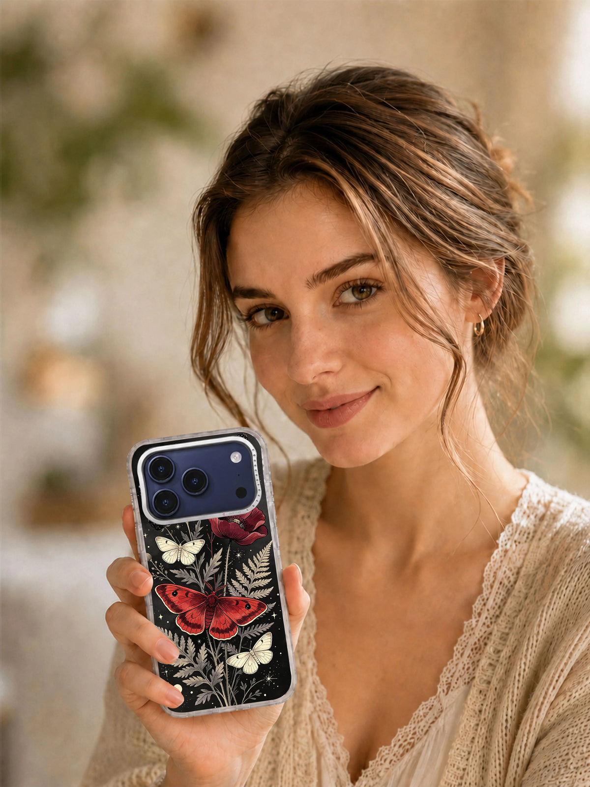 Lifestyle view of a woman holding the Crimson Moth Garden iPhone case