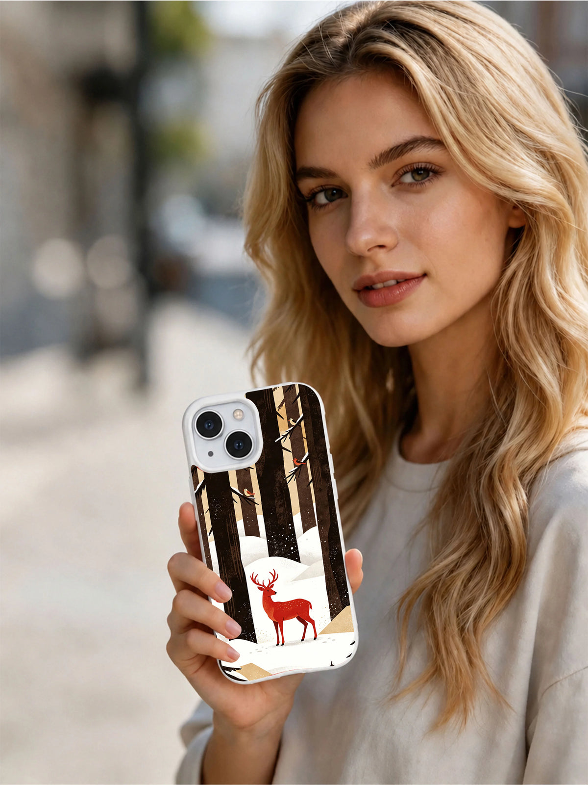Lifestyle view of a person holding the Crimson Watcher iPhone 13 case with red deer and winter forest art