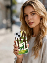 Woman holding an iPhone 13 case featuring the Emerald Stag Meadow artwork