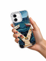 Evergreen Harbor iPhone 17 case held in hand with coastal Christmas artwork visible