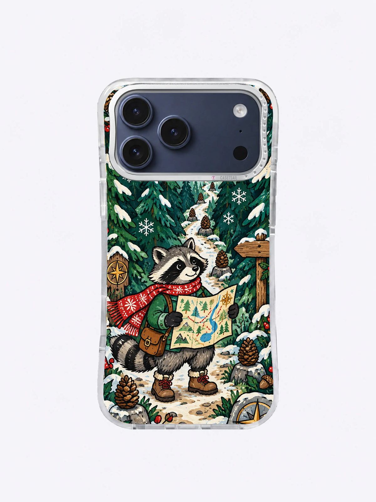 Compass Snow Path artwork on an iPhone case with a map-reading raccoon, layered pine trees, pinecone markers, snowy path, and golden compass rosette