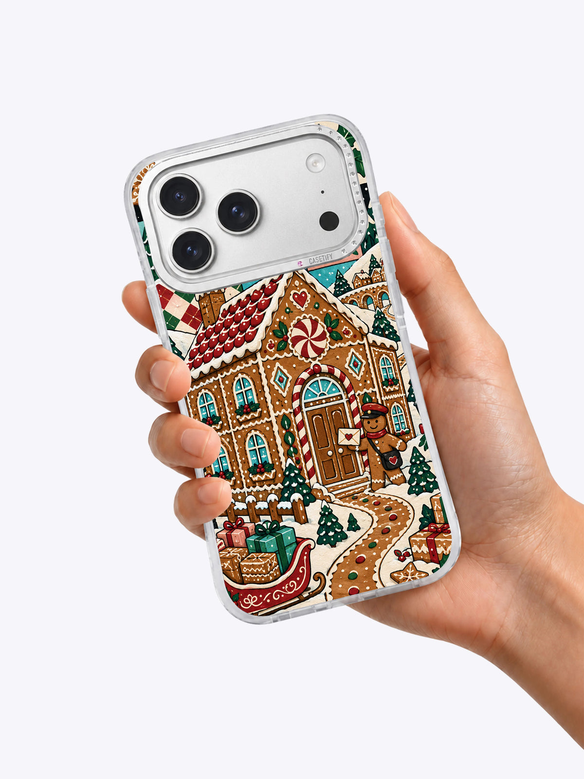 Gingerbread Post Office iPhone 17 Pro Max case held in one hand showing the festive cookie post office artwork