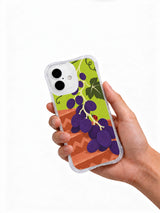 Hand holding a transparent iPhone 16 case with grape and ladybug artwork