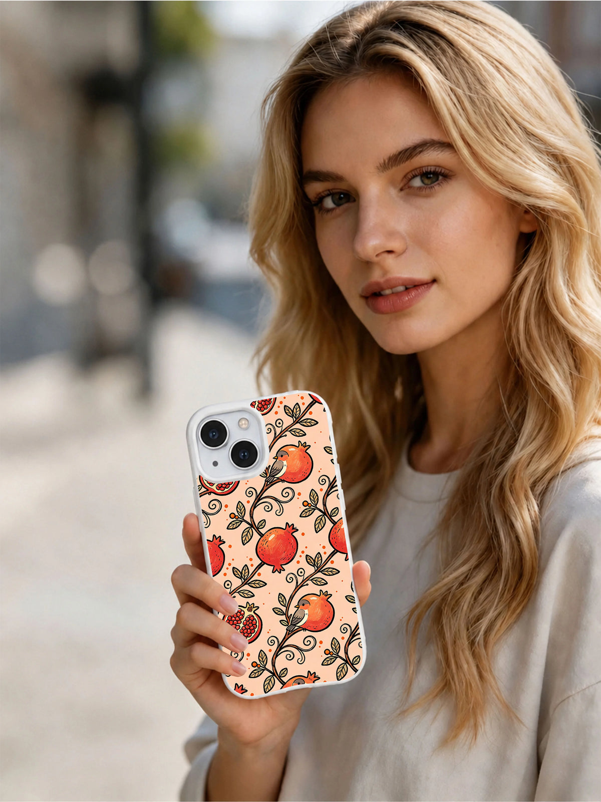 Model holding peach pomegranate iPhone 14 Plus case