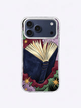 Open book pop-art iPhone case with navy cover, cream pages, burgundy impact cloud, forest-green rays, lavender grain, and gold stars