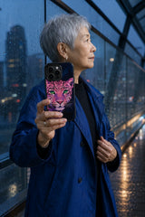 Adult woman holding Midnight Leopard Dream iPhone 13 Pro Max case on a rainy blue-hour footbridge