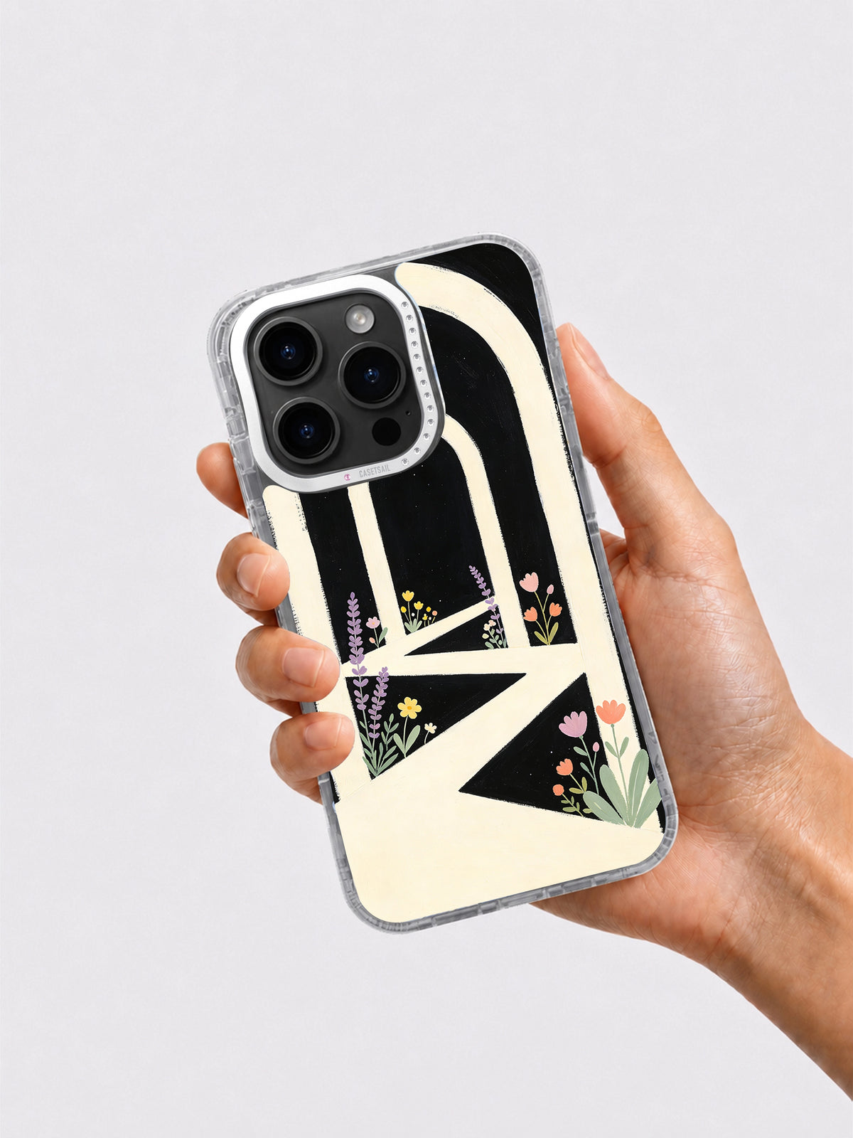 Hand holding black cream arch and flower iPhone 16 Pro Max case