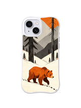 Orange bear beneath tall charcoal pines and angular warm-gray mountains on an iPhone 13 case