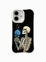 PhoneCasing Black Base Blue Rose fine art iPhone 16 Case, original Morrigan Vale old-school goth tattoo artwork featuring full skeleton staring at glowing luminous blue rose with falling silver petals on vintage textured black backdrop, scratch resistant glossy casing made in California