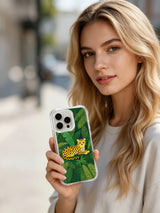 A person holding a phone case with a yellow spotted wild cat and green foliage.