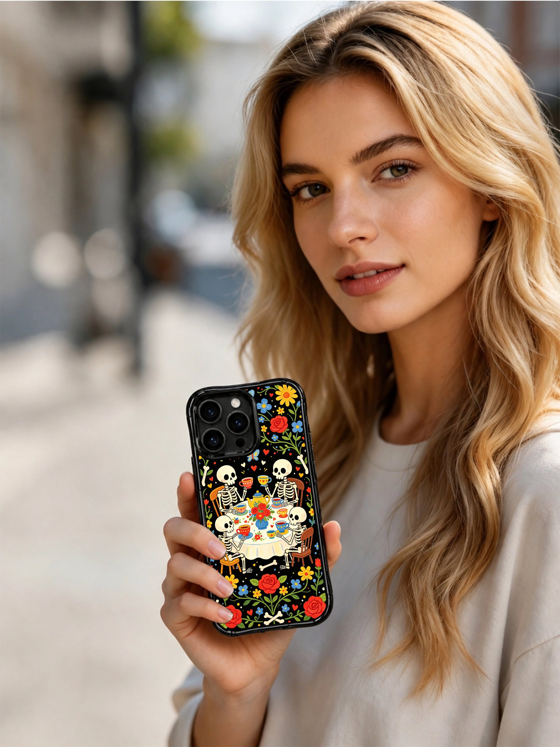 Whimsical dark fantasy skeleton gathering illustration on PhoneCasing iPhone 16 pro max case, folk art style with colorful flowers and tea party elements.