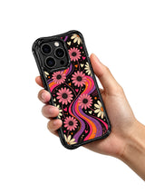 Siyah, çiçekli Tangerine Love Field telefon kılıfını tutan bir el.