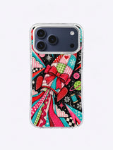 Patchwork Bow Comet artwork on an iPhone case with a red bow, stitched rocket panels, striped ribbon trails, stars, buttons, and checkerboard shapes