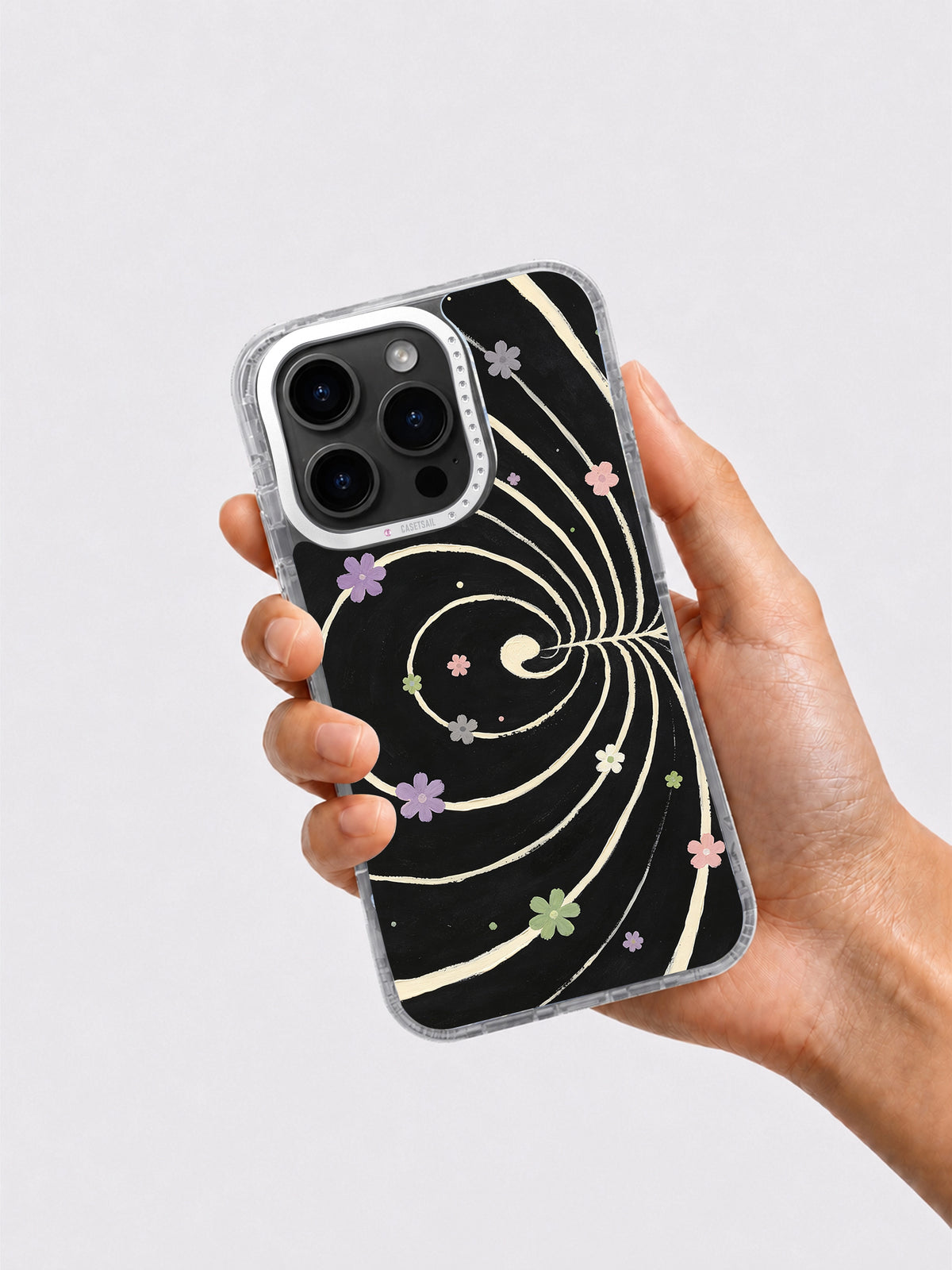 Hand holding black cream and pastel floral spiral iPhone case