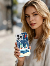 Lifestyle view of a person holding The Little Polar Globe iPhone 15 Pro case with penguin and snowy fir artwork
