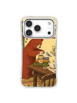 Brick-red bear, blue bird and three cups on a warm cottage table on an iPhone 17 Pro case