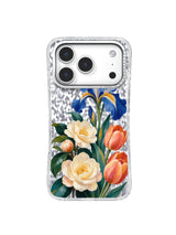 Cobalt irises rise behind cream camellias and coral tulips on a transparent iPhone 17 Pro case