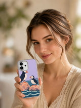 Lifestyle portrait holding the Two Seats Above the Tide illustrated iPhone 17 case