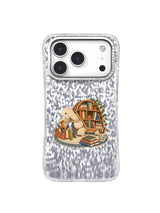 Cream turtle sorting ribbon bookmarks beside a shell bookshelf on an iPhone 17 Pro case