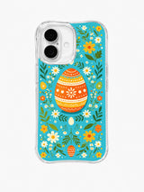 Wildflower Egg Festival / Orange Folk Egg Garden: A large orange patterned egg centered inside a green garland with yellow and white flowers.