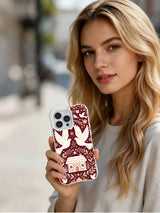 Lifestyle view of The Winter Dove Garden iPhone 13 Pro case with mirrored birds and burgundy folk pattern