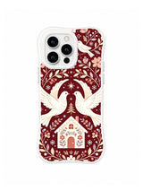 Mirrored white doves over a pointed folk cottage framed by flowers leaves and stars on burgundy iPhone 13 Pro case